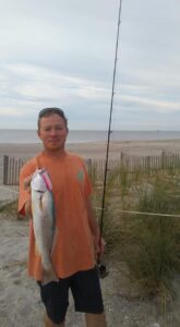 Marshall holding a trout with a trout love lure with the Atlantic Ocean in the background